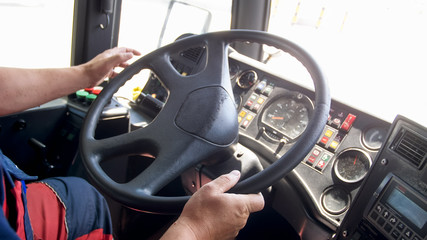 Closeup photo of man holding hands on truck steering wheel