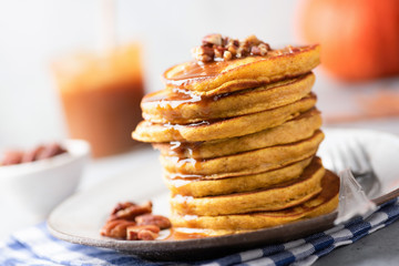 Tasty pumpkin pancakes with caramel sauce and nuts. Selective focus. Autumn comfort food, american Thanksgiving day breakfast