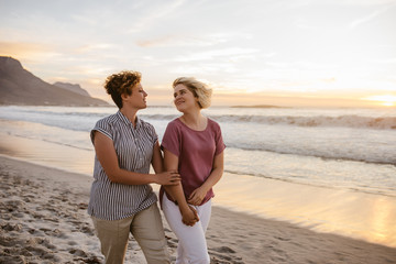 Smiling lesbian couple enjoying a romantic walk along a beach