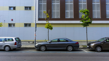 cars parked on the road against a background of a new urban building. a street urban landscape...