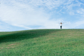 Fototapeta premium Standing woman raised her hands on the mountain, natural green and beautiful sky.