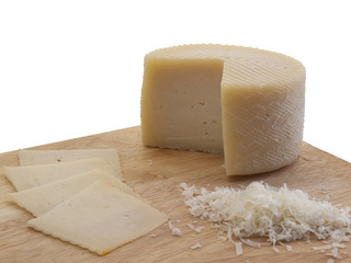Queso de oveja semicurado cortado en lonchas y ralladuras sobre una tabla de corte de madera