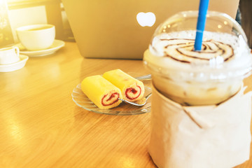A cafe table with Coffee and jam roll.