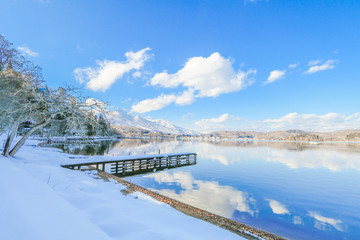 Fototapeta premium Beautiful fresh snow in winter around the mountains Lake with blue sky background, Nagano Prefecture, Japan.