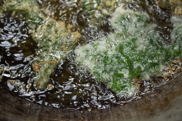 Breaded seaweed deep frying in oil in a cast iron frying pan