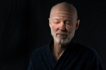 portrait of senior sleeping man in bathrobe on black background