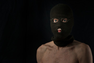 portrait of senior retired burglar wearing only a balaclava on black background