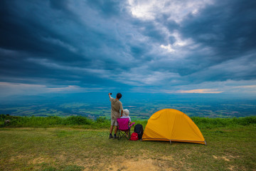 The traveler with her tent on the cliff in the evening.