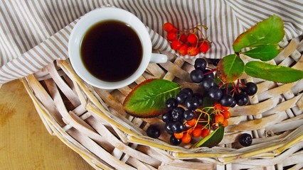 Useful drink of Rowan.Red and black ashberry on a wicker background.