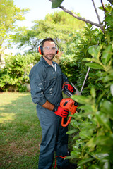 handsome young man gardener trimming hedgerow in a garden park outdoor