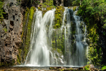 Fototapeta na wymiar Beautiful waterfall flowing down a green rock wall