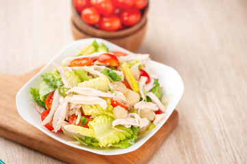 Fresh and delicious homemade chicken salad with tomatoes and pomelos in wooden background, concept of healthy and diet, top view, copy space