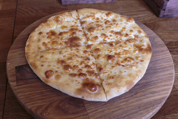 Fresh cheese pizza on a wooden plate, Italian and Caucasian traditional appetizer, ready to eat.