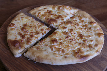 Fresh cheese pizza on a wooden plate, Italian and Caucasian traditional appetizer, ready to eat.