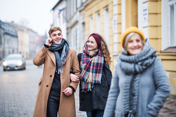 Grandmother and teenage grandchildren walking down the street in winter.