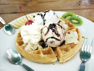 Waffle topped with chocolate chips ice cream , banana and wipe cream