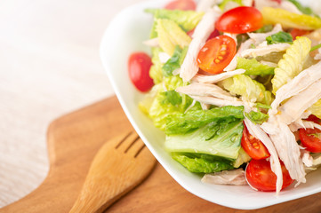 Fresh and delicious homemade chicken salad with tomatoes and pomelos in wooden background, concept of healthy and diet, top view, copy space