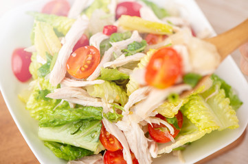 Fresh and delicious homemade chicken salad with tomatoes and pomelos in wooden background, concept of healthy and diet, top view, copy space