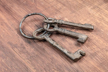 A photo of old keys on a ring, on a dark rustic texture with copy space