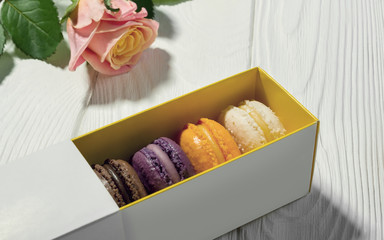 Macarons box and pink rose on wooden table