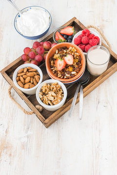 Paleo grain free nut and fruit granola in a tray with fruits and berries, nut milk, coconut yogurt, copy space, top view, selective focus