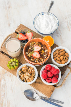 Oat free paleo nut and fruit granola served with fruits and berries, nut milk, coconut yogurt, vertical, selective focus