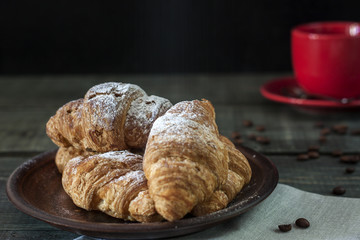 Cup of cappuccino coffee and croissant on dark table