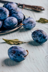 Plums on wooden surface with leaves