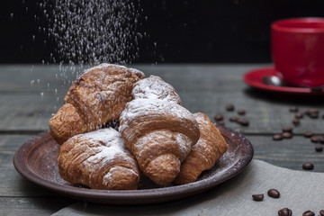 Cup of cappuccino coffee and croissant on dark table
