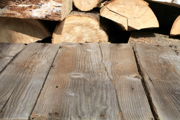 Empty wooden deck table with pile of firewood in backround