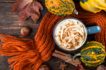 Pumpkin latte with spices and whipped cream on top on a wooden background. Copy space. Autumn or winter hot drink.