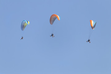 Paragliders flying with a paramotor over clear blue sky