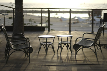 Wattled tables and chairs on wooden terrace in cafe.