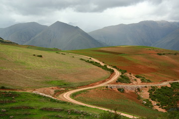 S curved country road cut deep through agriculture area into the valley of Andes mountains, Cusco, Peru - obrazy, fototapety, plakaty