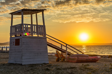 Fototapeta premium Early morning, dramatic sunrise over sea and house for rescuers on the beach.