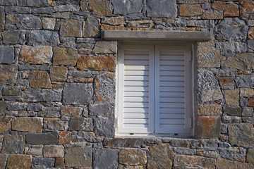 Weißes Fenster in einer Mauer mit unregelmäßigen Strukturen