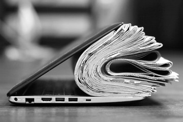 Open laptop and stack of newspapers. Daily journals with news and personal computer. Concept for...