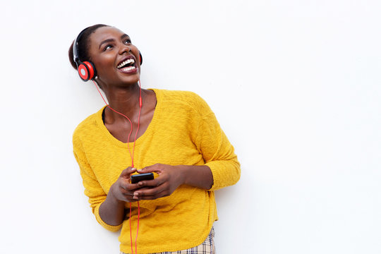 Smiling Young African Woman Listening To Music With Headphones And Mobile Phone Against Isolated White Background