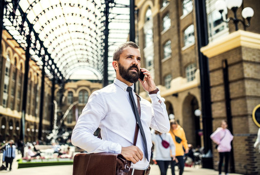 Businessman with smartphone on the trian station in London, making a phone call.