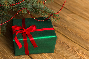 Green gift with red ribbon, Christmas tree and decorations on the table. New year.