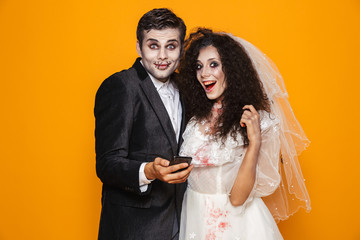 Surprised happy bride and groom in hallowen costumes looking camera isolated