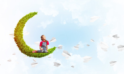 Concept of careless happy childhood with girl on green moon