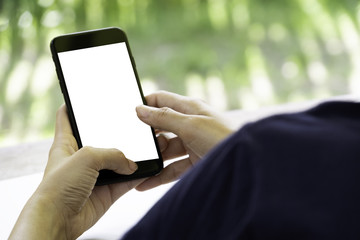 Hand holding, toching or working with the black mobile phone with blank white screen on the outdoor background.