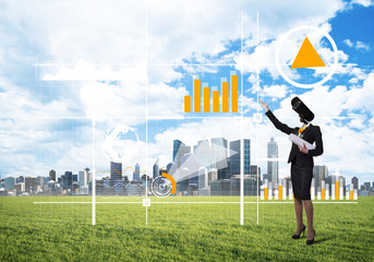 Camera headed woman standing on green grass against modern cityscape