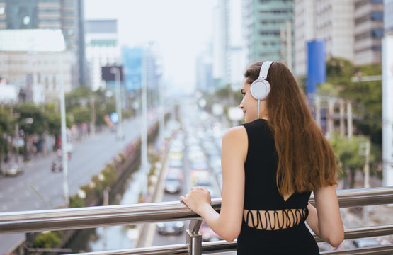 Beautiful woman using headphones and listening to music in the city