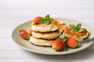 Curd pancakes with strawberries and mint on a plate