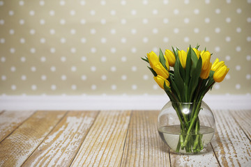 A bouquet of yellow tulips in a vase on the floor. A gift to a w