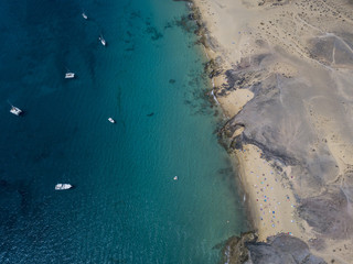 Vista aerea delle coste frastagliate e delle spiagge di Lanzarote, Spagna, Canarie. Strade e sentieri sterrati. Bagnanti in spiaggia. Oceano Atlantico. Papagayo