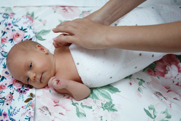 Mother's hands gently swaddles the baby