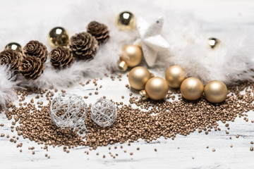 golden and white christmas balls and white feathers on wooden white background